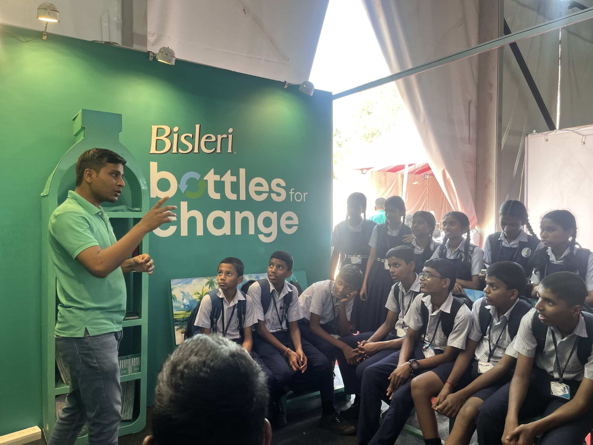 Schoolchildren sorting plastic bottles into bins in a school courtyard