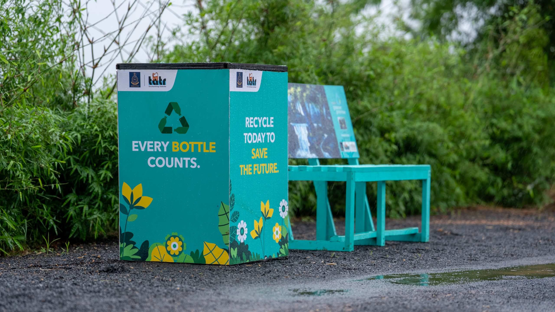 A Bottles for Change recycling bin and recycled plastic bench installed on a forest trail